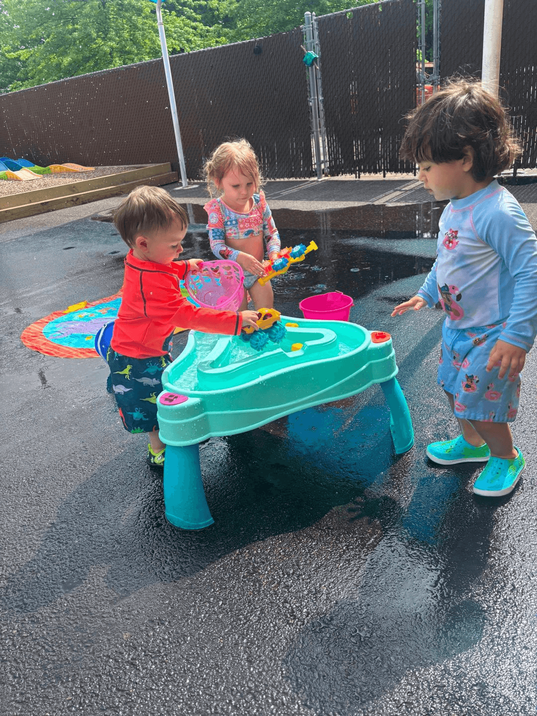 Campers playing at an outdoor water table on a sunny day at Bright Beginners Academy Bensalem.