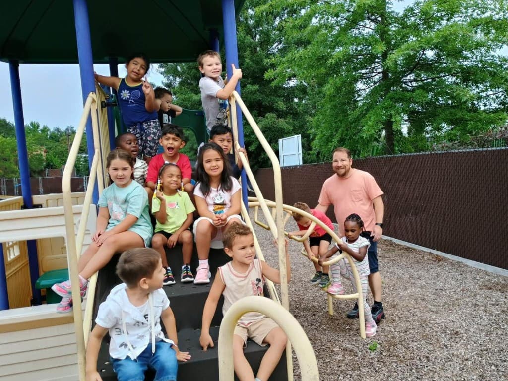 Children and a teacher posing together on the playground at Bright Beginners Academy Bensalem